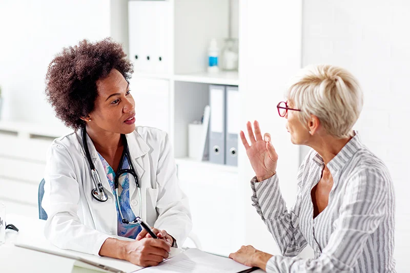 A woman and doctor talk at a desk